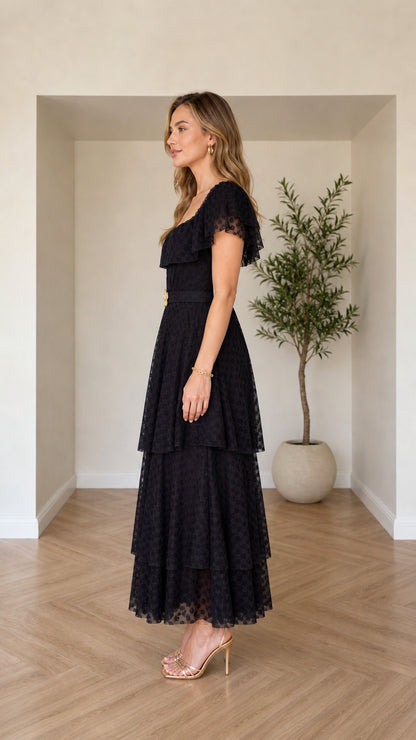 Side profile of woman wearing black ruffle tiered maxi dress