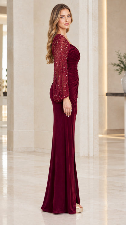Side view of woman wearing burgundy velvet evening dress with slit