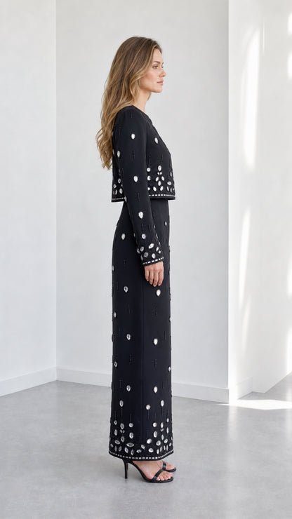 Side profile of woman wearing black crystal beaded long sleeve maxi set with heels