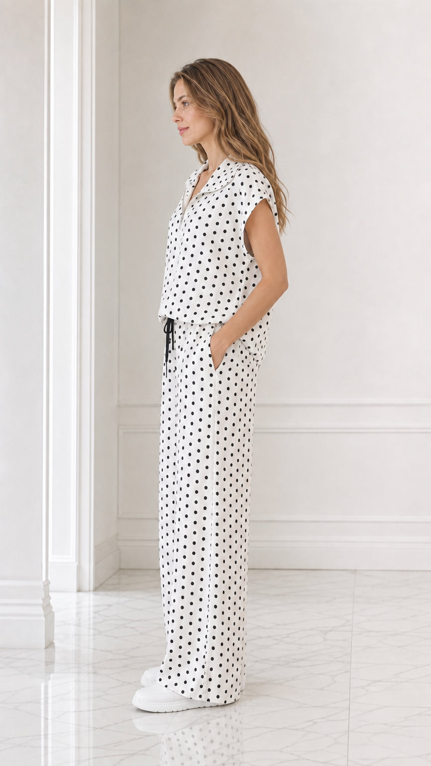 Side profile view of model wearing white polka dot collared top and wide leg pants
