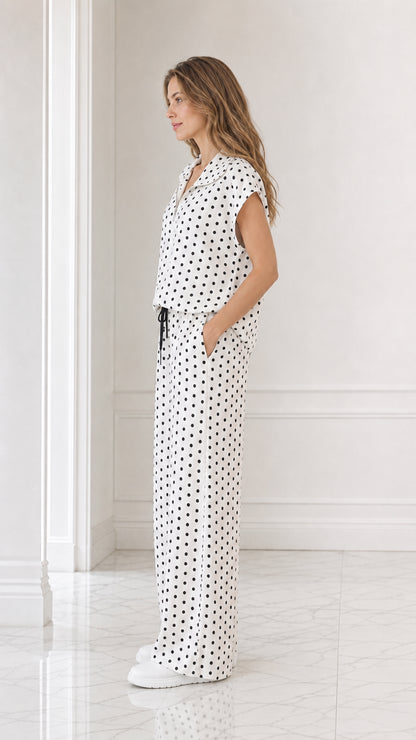 Side profile view of model wearing white polka dot collared top and wide leg pants