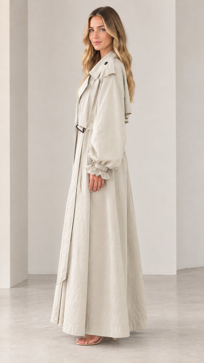 Side 3/4 view of elegant beige maxi trench coat showing dramatic sweeping hem