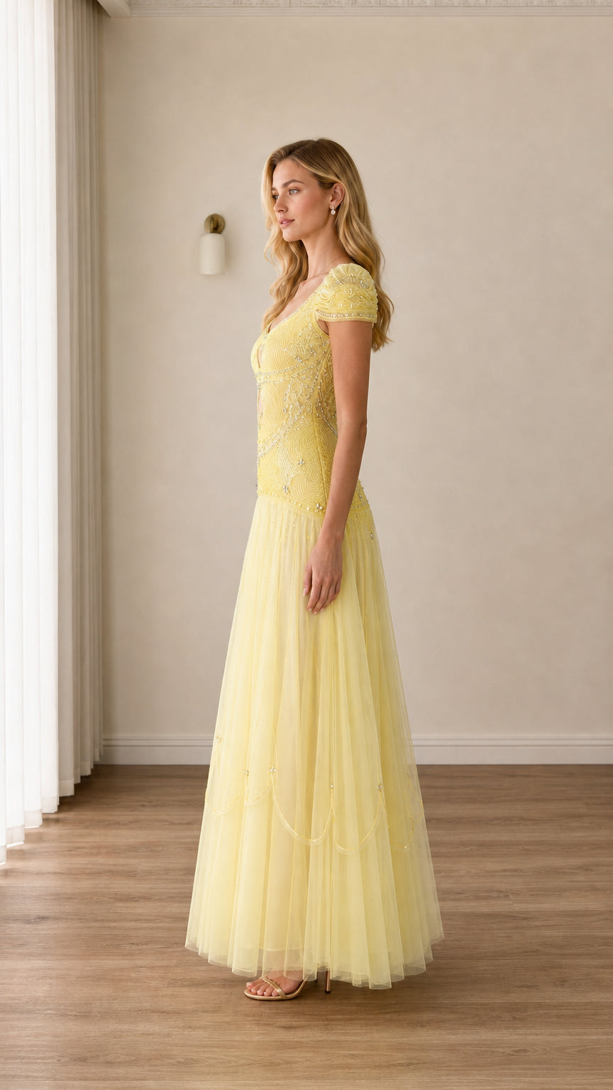 Side profile view of woman modeling pastel yellow beaded floor-length formal dress