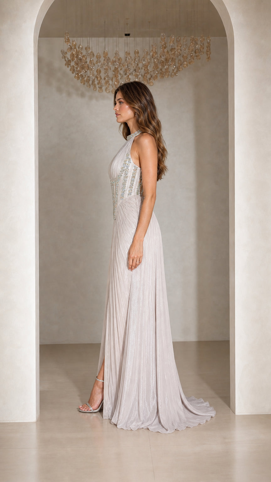 Side profile view of woman modeling Silver halter pleated maxi formal dress