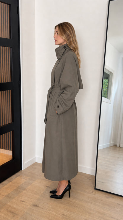 Side profile view of olive green maxi trench coat showing longline drape and belt tie