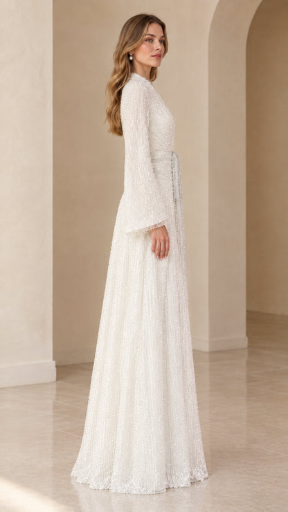 Side profile of model in white shimmering floor-length sequin gown with flared sleeves
