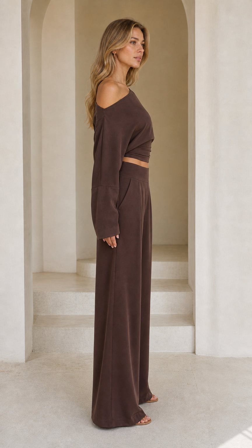 Side profile view of chocolate brown two-piece matching crop top and wide-leg trousers