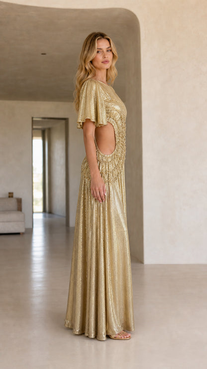 Side profile view of woman in a gold metallic maxi dress