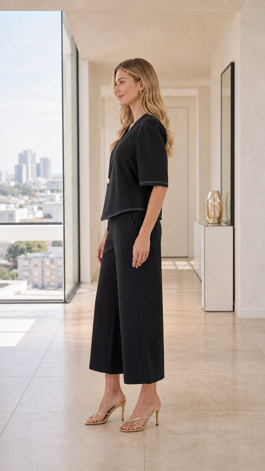 Side profile of black tailored two-piece set featuring asymmetric top and wide-leg trousers
