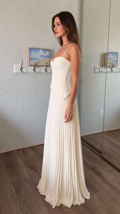 Side profile of woman wearing white lace corset bodice pleated maxi dress