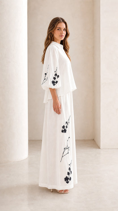 Side profile view of woman wearing white embroidered matching two-piece set