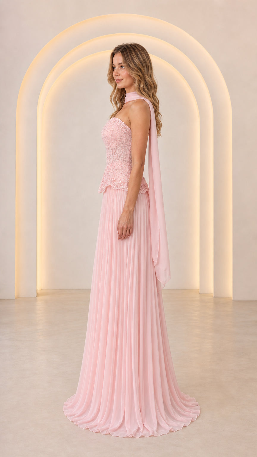 Side profile view of Blush Pink formal strapless gown with draped neck scarf and pleated maxi skirt