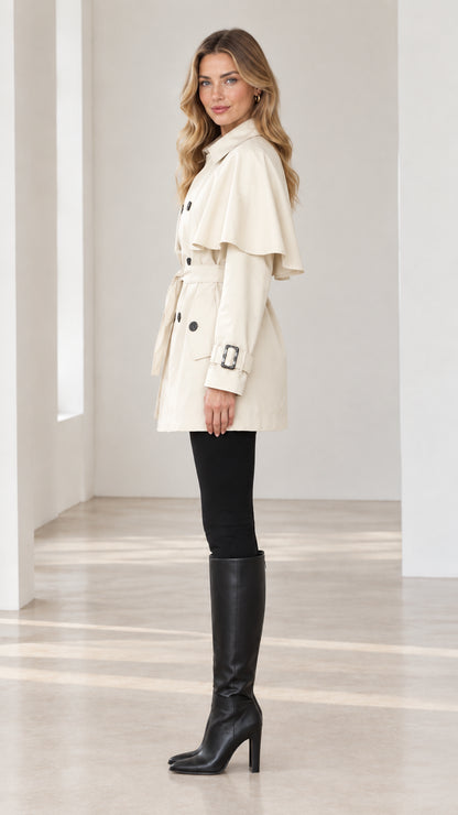 Side-angle view of Cream capelet trench coat showing shoulder layer and sleeve cuff buckles