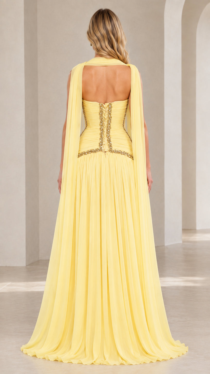 Back view of model wearing pastel yellow strapless evening gown showcasing open back design