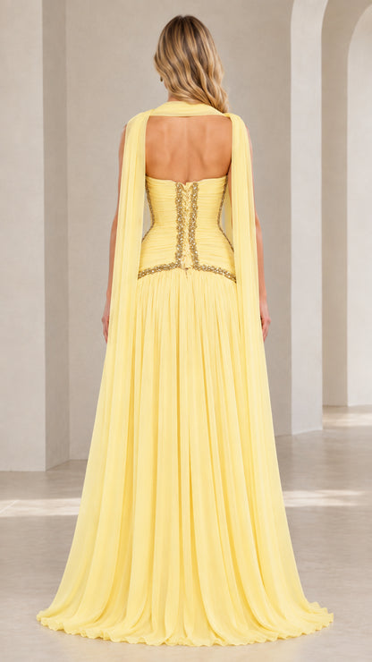 Back view of model wearing pastel yellow strapless evening gown showcasing open back design