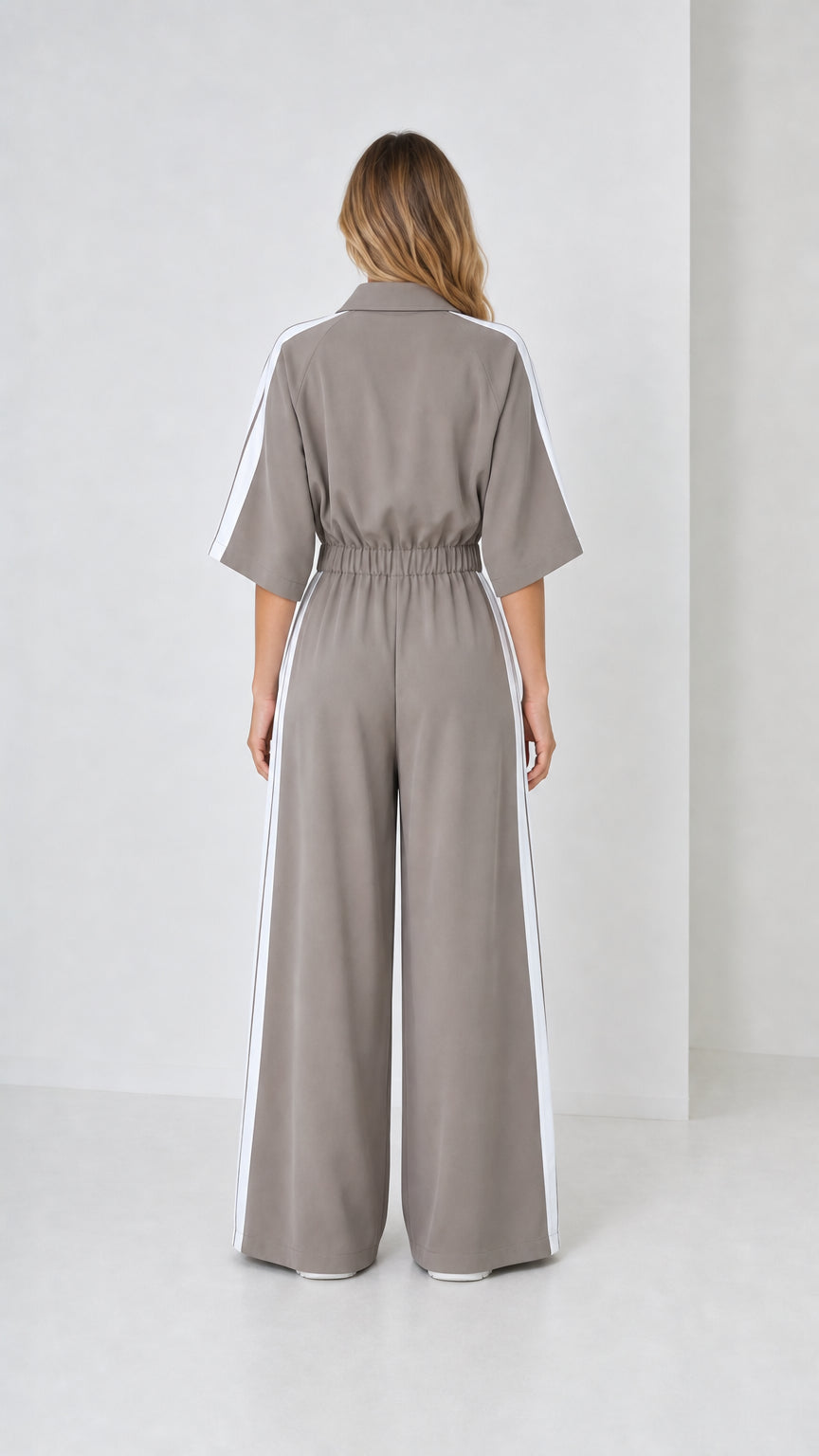 Back view of woman wearing taupe grey wide leg track jumpsuit