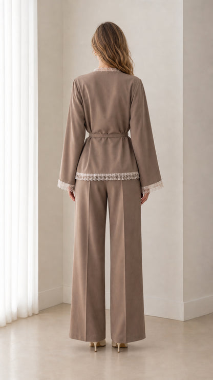 Back view of woman wearing taupe lace-trimmed blazer and pleated wide-leg trousers