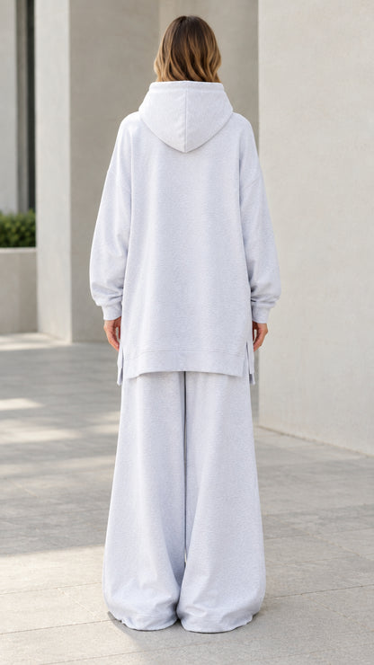 Back view of woman wearing light heather grey hooded sweatshirt set with relaxed wide-leg bottoms