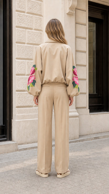 Back view of model wearing beige two-piece suit set with embroidered sleeves and wide-leg pants