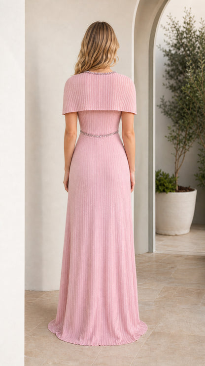 Back view of woman wearing pink pleated maxi dress with capelet overlay