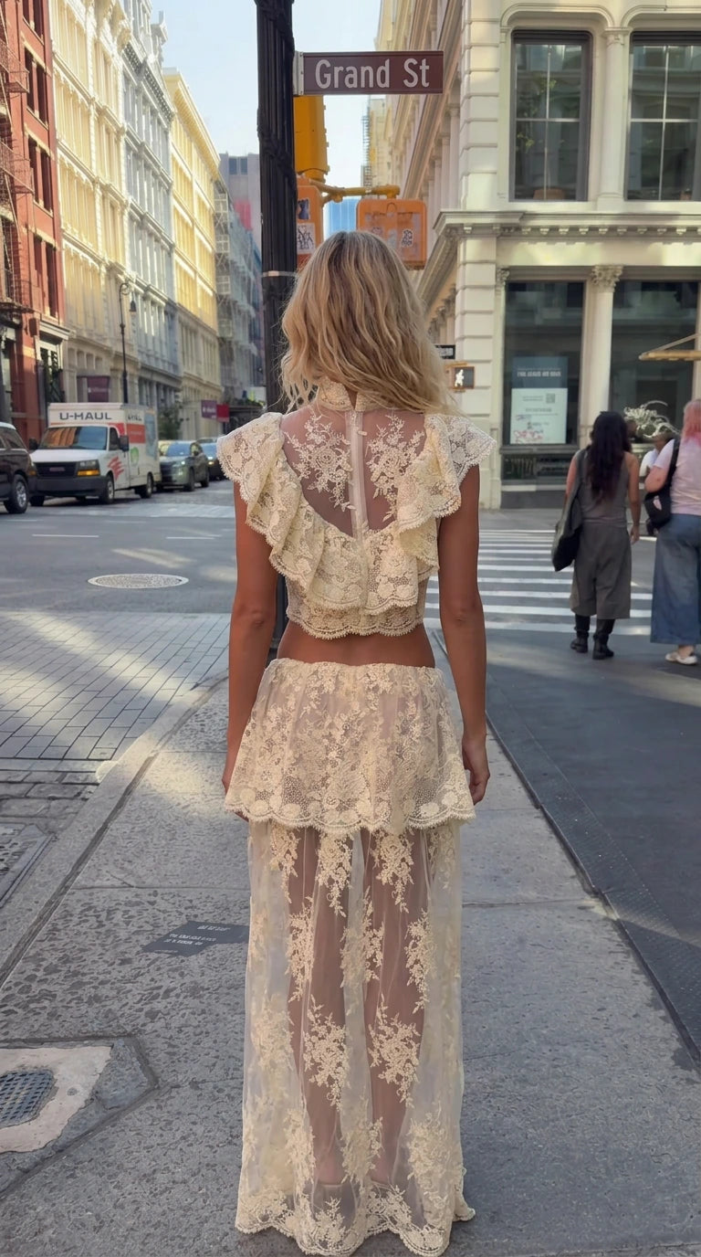 Back view of model wearing cream ruffled lace crop top and sheer lace skirt