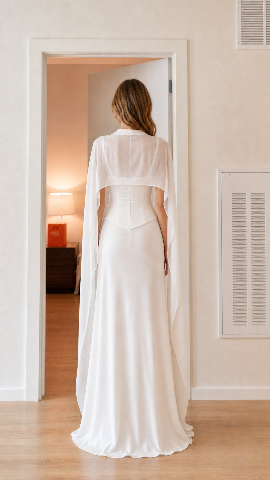 Back view of model showing sheer flowing cape on white formal gown