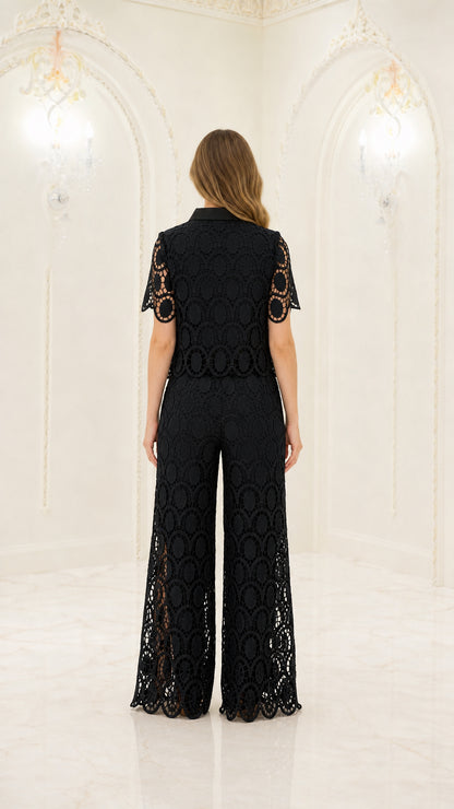 Back full-length view of woman wearing black geometric lace short sleeve shirt and wide-leg trousers