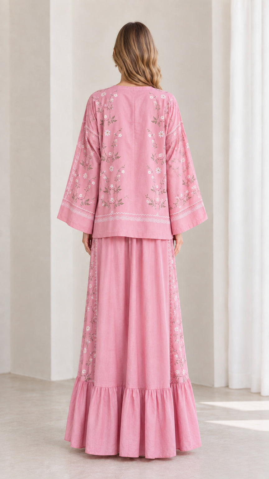 Back view of model wearing pink relaxed long sleeve top and tiered maxi skirt