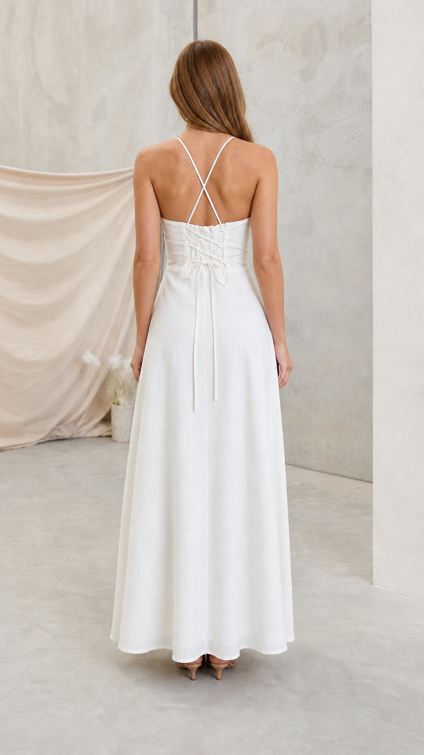 Back view of white halter maxi dress showing criss-cross straps and corset tie back