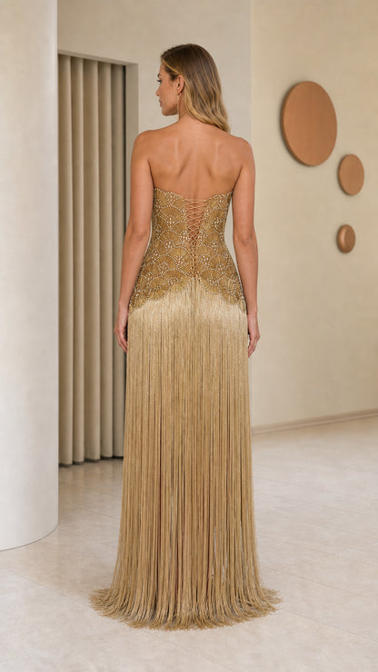 Model wearing gold beaded fringe evening gown back view
