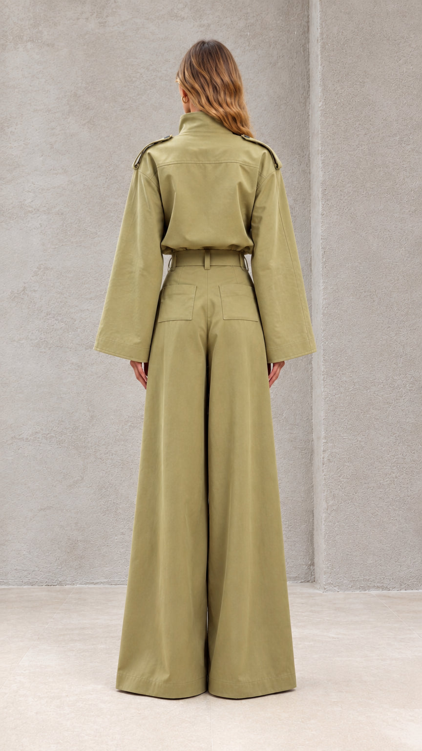 Back view of model wearing sage green jumpsuit with pleated wide-leg palazzo pants