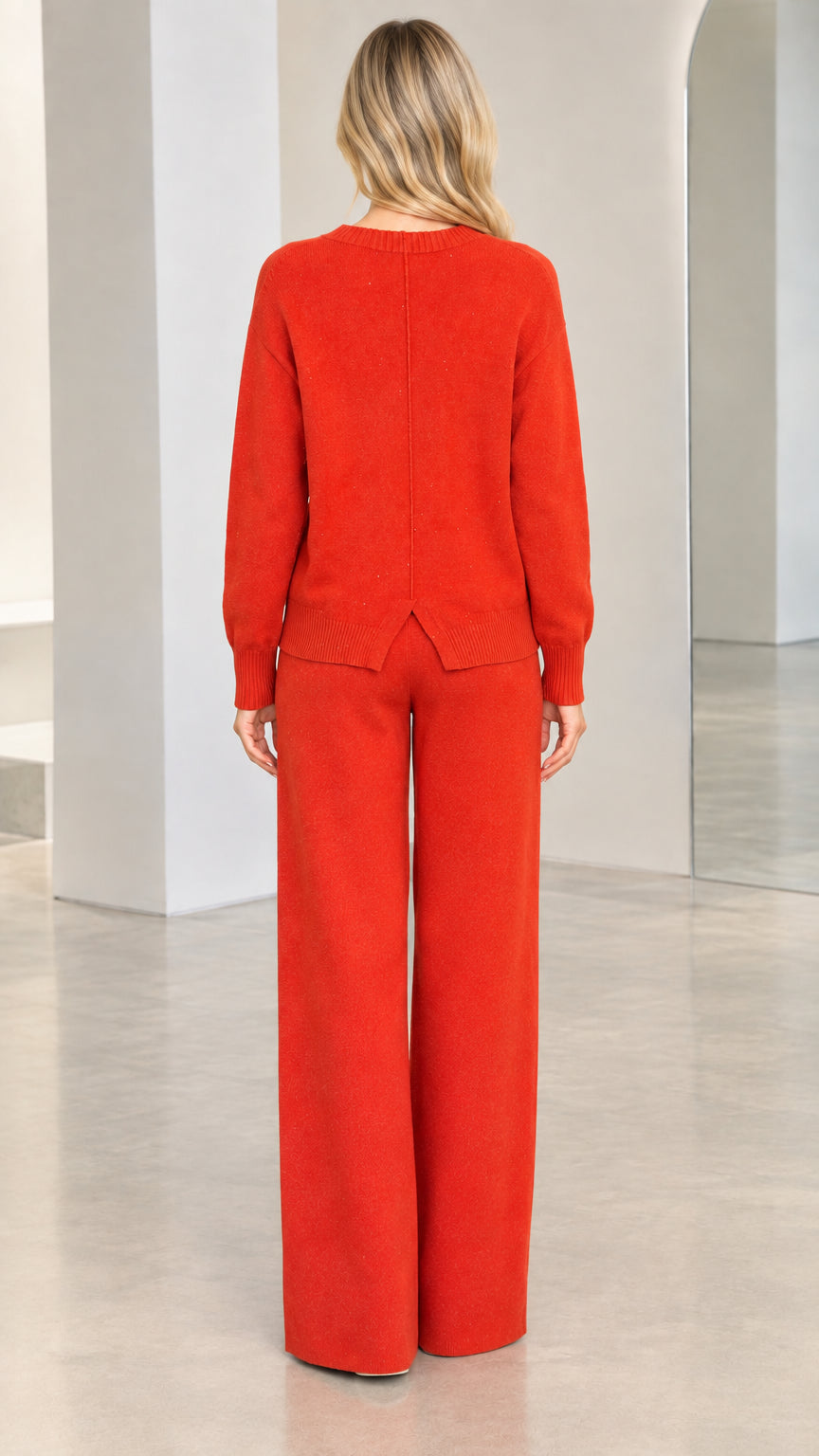 Back view of rust red knit set highlighting the sweater back seam and split hem