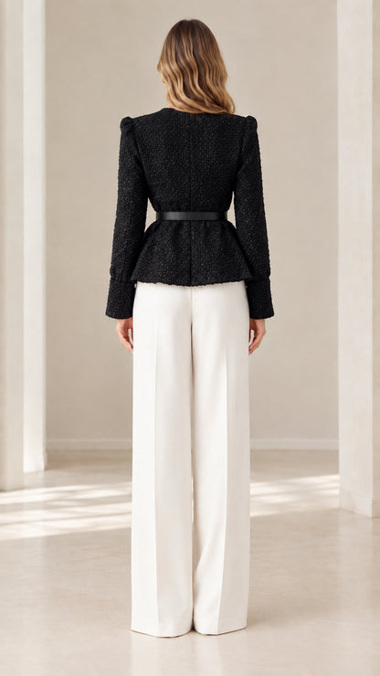 Back view of model in black collarless tweed peplum jacket and white wide-leg pants