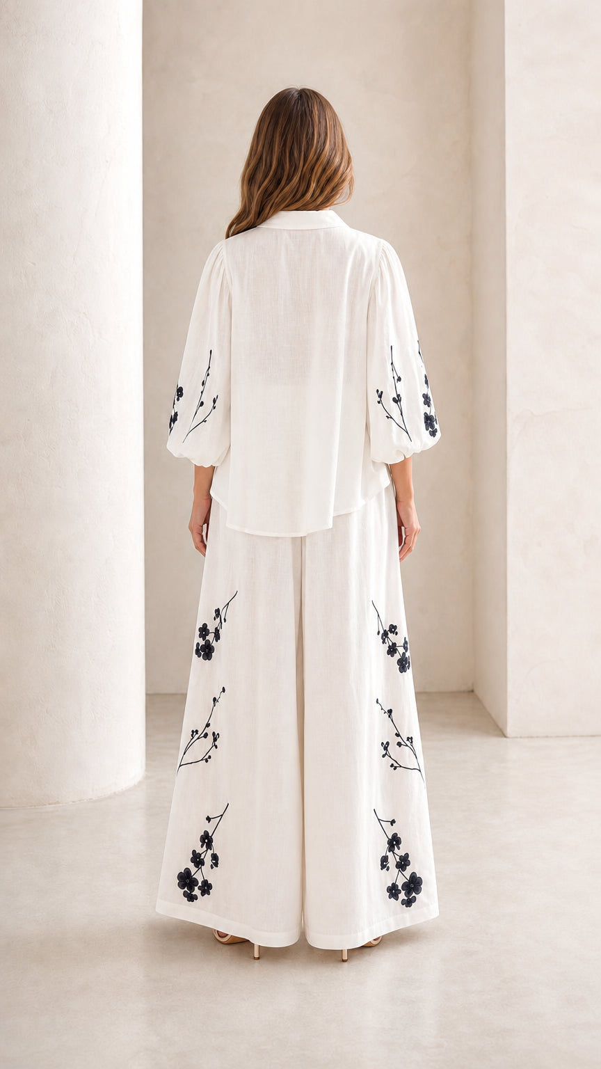 Back view of woman wearing white embroidered top and wide-leg trousers