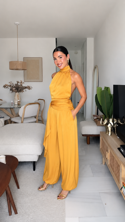 Angled front view of mustard halter jumpsuit with wide legs and side pockets