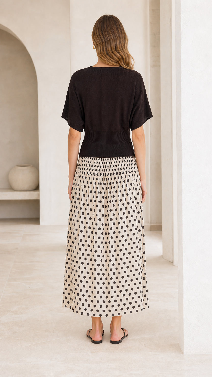 Back view of woman wearing two-tone polka dot maxi dress in cream