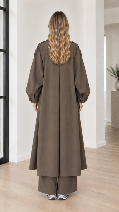 Back view of woman wearing full-length olive brown duster coat with inverted pleat