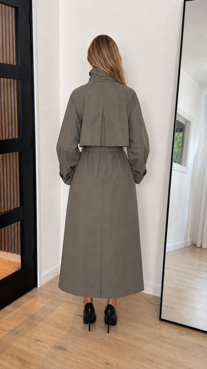 Back view of olive green maxi trench coat featuring storm flap and full length cut