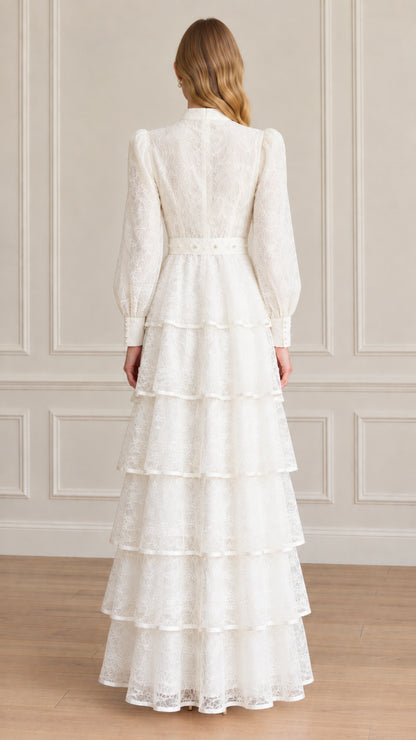 Back view of model showing full length white tiered lace dress with high collar