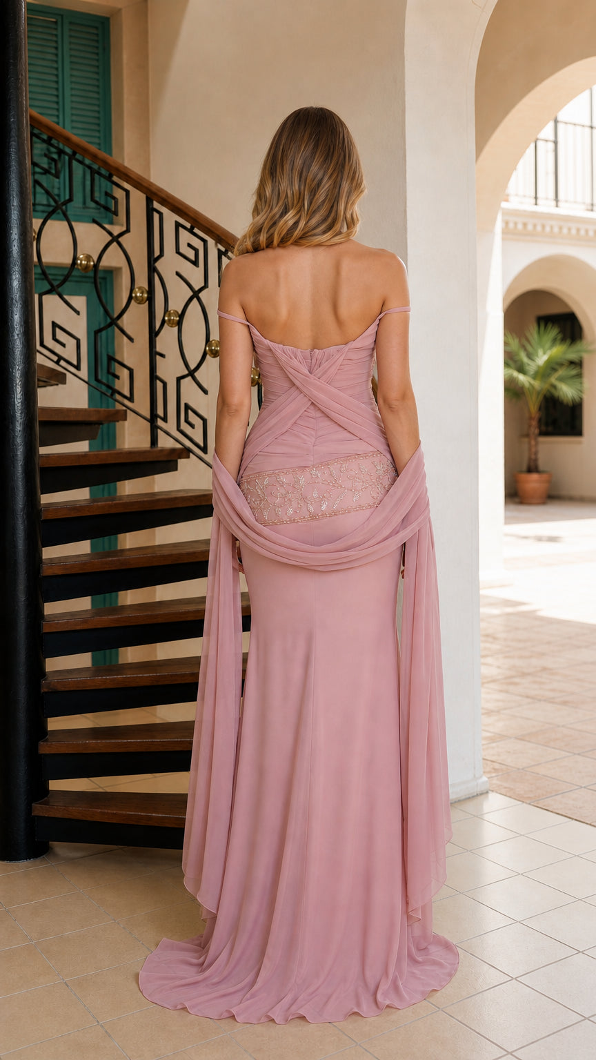 Back view of dusty rose strapless gown highlighting low back ruched detail and flowing hem
