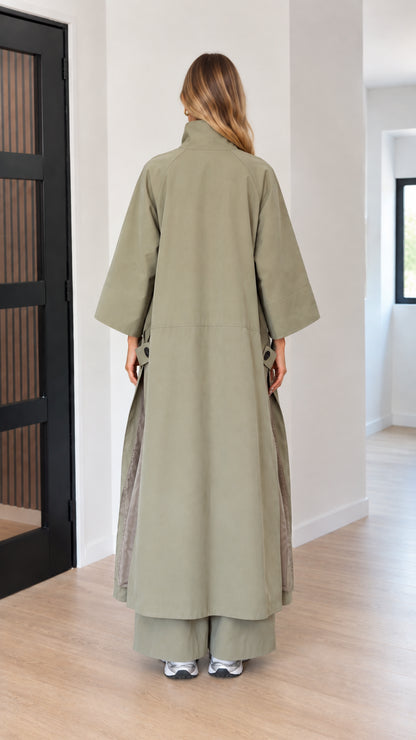 Back view of woman wearing full-length sage green cape duster coat