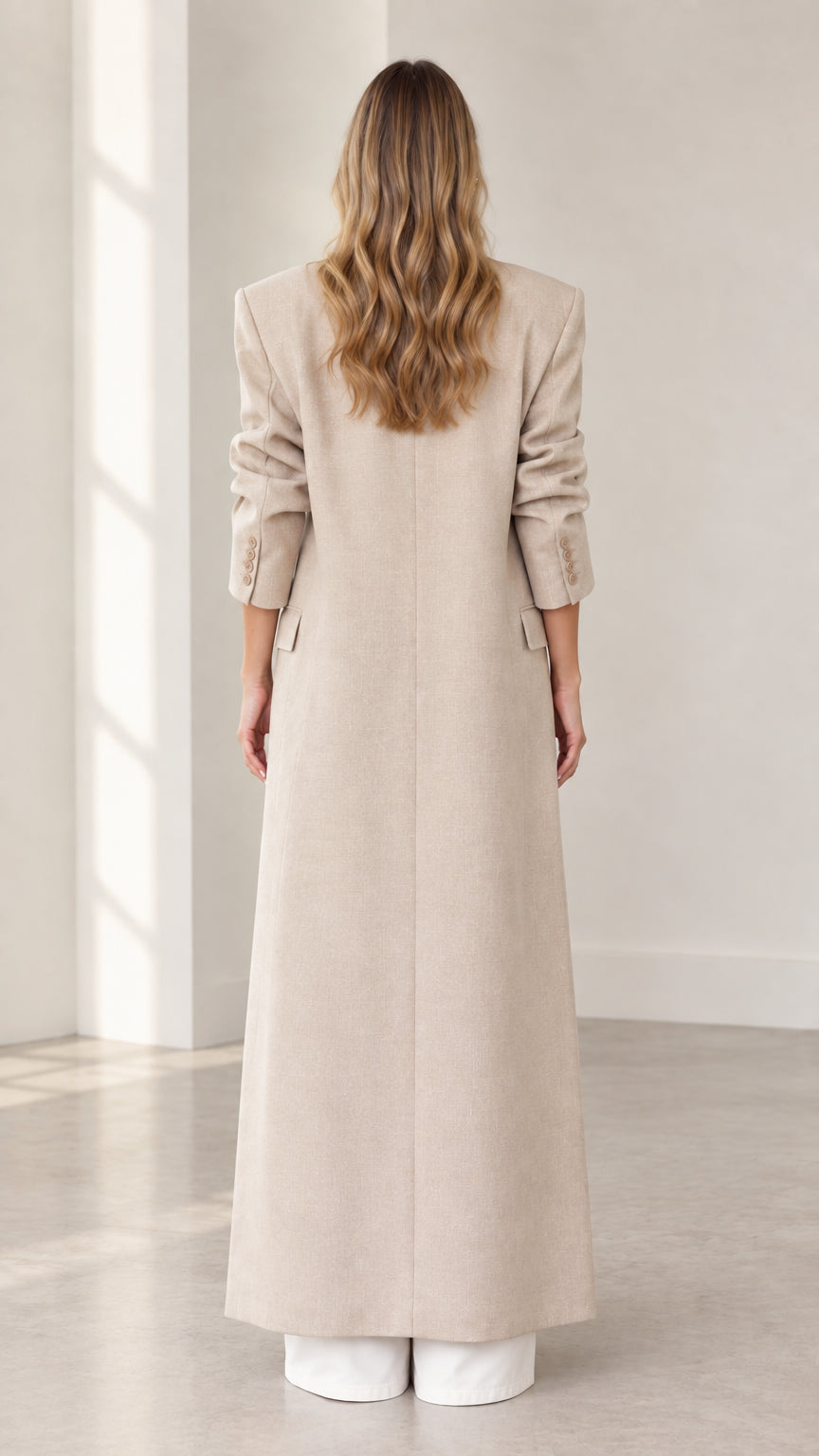 Back view of floor-length beige overcoat showing straight silhouette