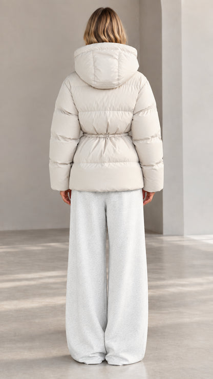 Back view of woman wearing off-white hooded puffer jacket with cinched waist