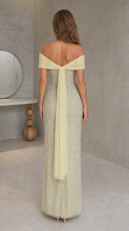 Back view of model in yellow beaded gown with flowing back scarf