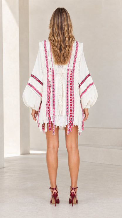 Back view of model showcasing embroidered back detail of cream fringe cardigan