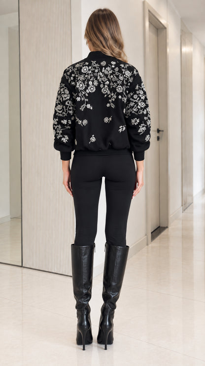 Back view of model showing detailed floral embroidery across back of black bomber jacket