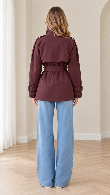 Back view of burgundy short trench coat showing storm flap and waist belt