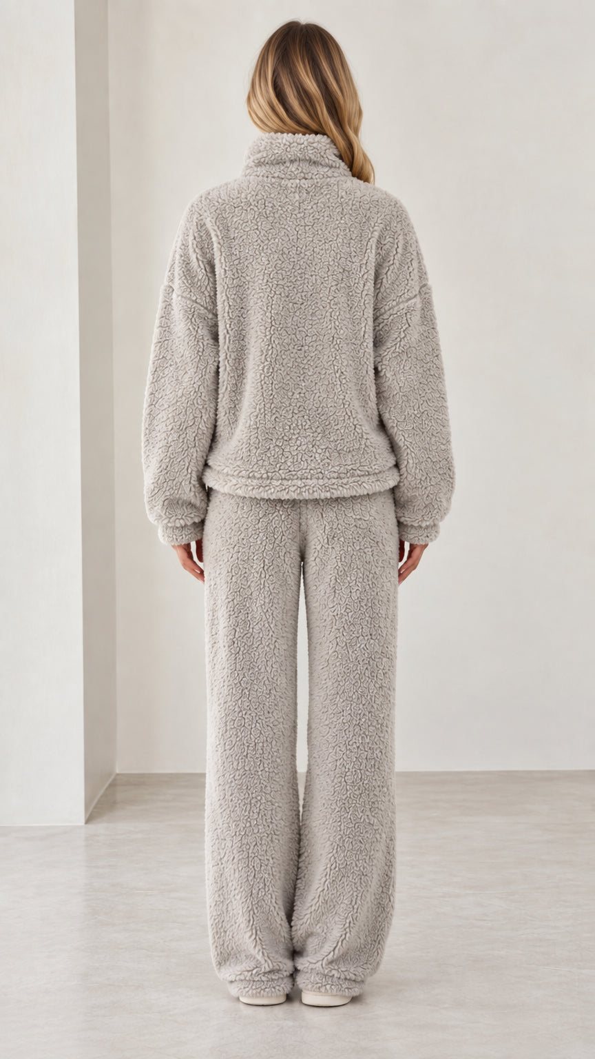 Back view of model wearing light gray fleece pullover and wide-leg pants