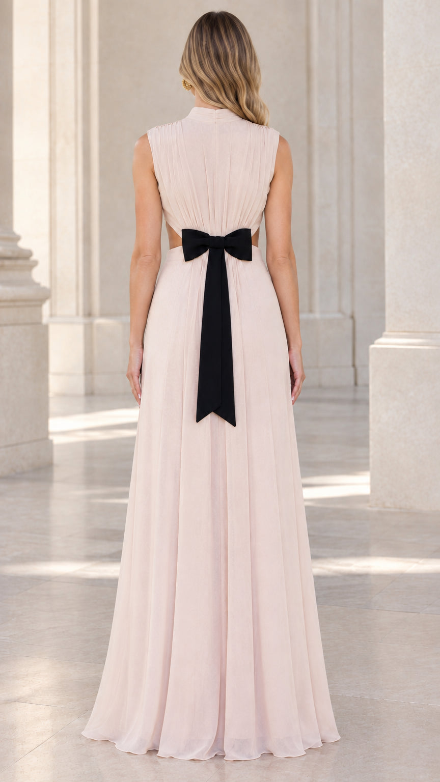 Back view of model wearing blush pink pleated evening gown with bow detail