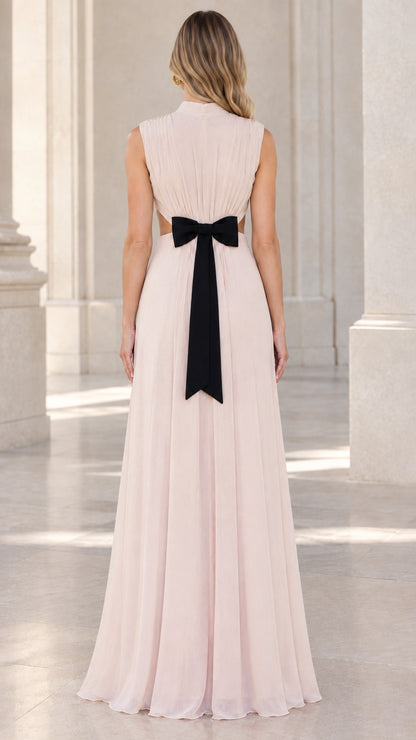 Back view of model wearing blush pink pleated evening gown with bow detail